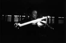 Anderson Playing the Neon Violin, 1983, black and white photograph from 'United States, 1-4' at Brooklyn Academy of Music, Brooklyn, NY, Courtesy Laurie Anderson & Sean Kelly Gallery, New York, Photo: Hogers/Versluys